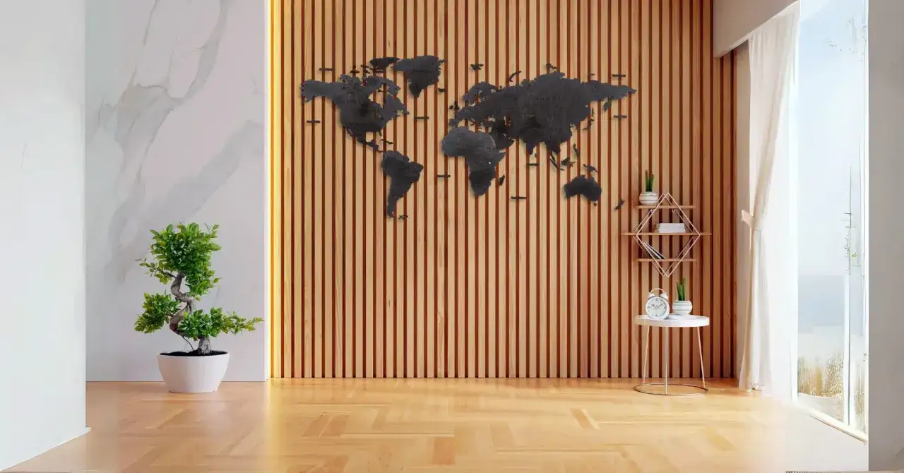 Ściana z pionowych drewnianych listew, na której wisi czarna mapa świata. Obok stoi drzewko bonsai i stolik z zegarem.