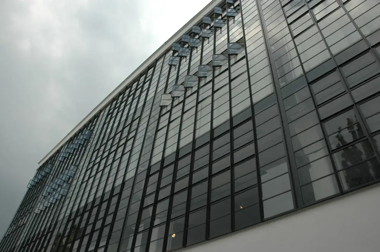 Szklana fasada budynku, przykład modernizmu. Charakterystyczne okna wychylne tworzą ciekawy wzór.