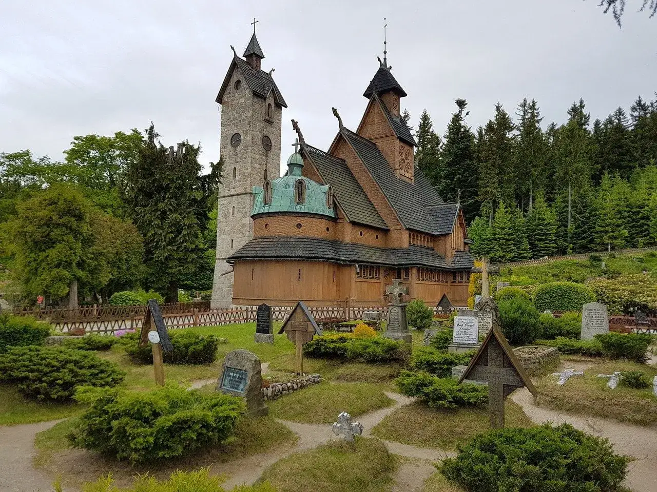 Drewniana świątynia Wang w Karkonoszach, otoczona cmentarzem i lasem.