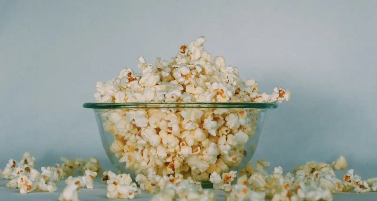 Miska pełna popcornu, rozsypanego wokół. Czy koty mogą jeść popcorn? To pytanie nurtuje wielu właścicieli.