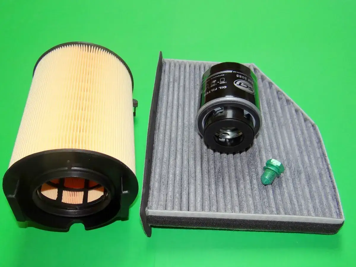 Zwei Auto-Filter (Öl- und Innenraumfilter) und eine grüne Schraube auf grünem Hintergrund.