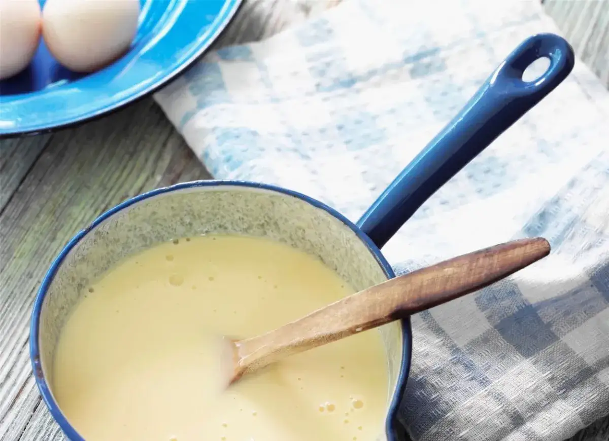 Gotowy budyń w garnuszku, z jajkami w tle. Zastanawiasz się, ile może stać budyń w lodówce?