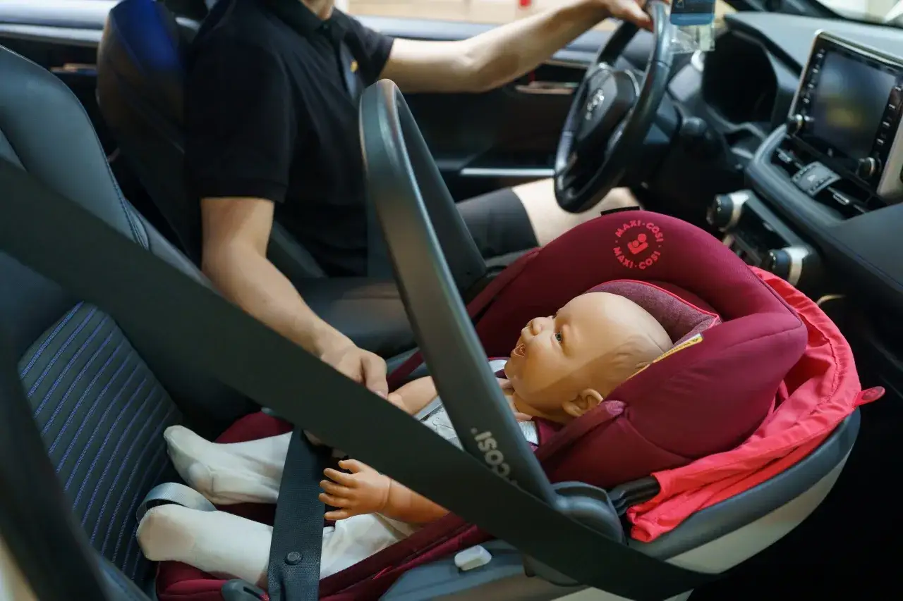 Fotelik dziecięcy z manekinem zamontowany z przodu samochodu za pomocą systemu isofix.