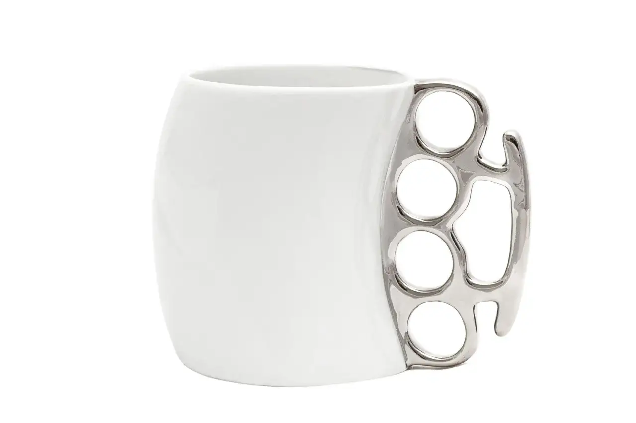 Biały kubek z metalowym uchwytem w kształcie kastetu.