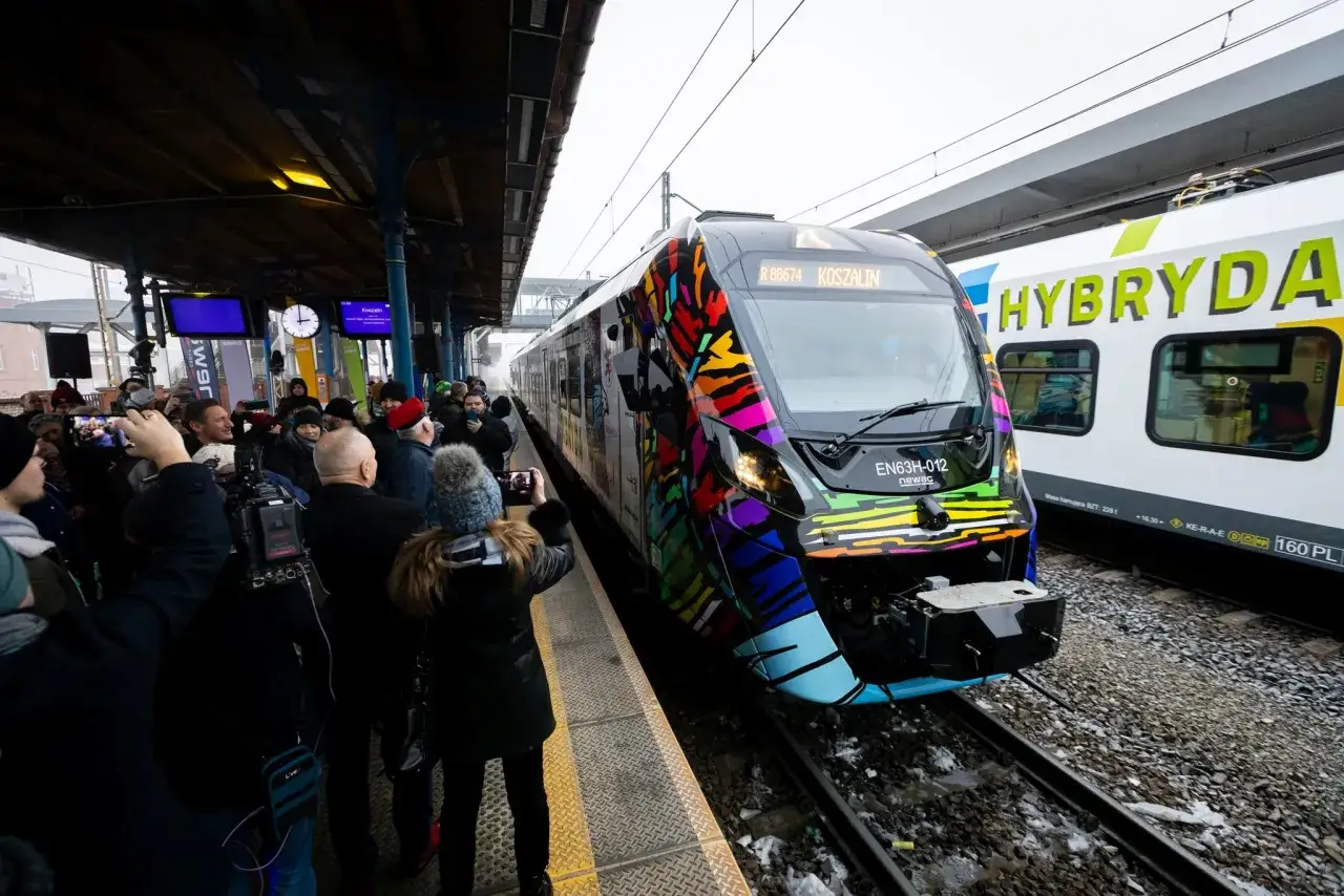 Kolorowy pociąg Hyperion na stacji, otoczony przez ludzi robiących zdjęcia.
