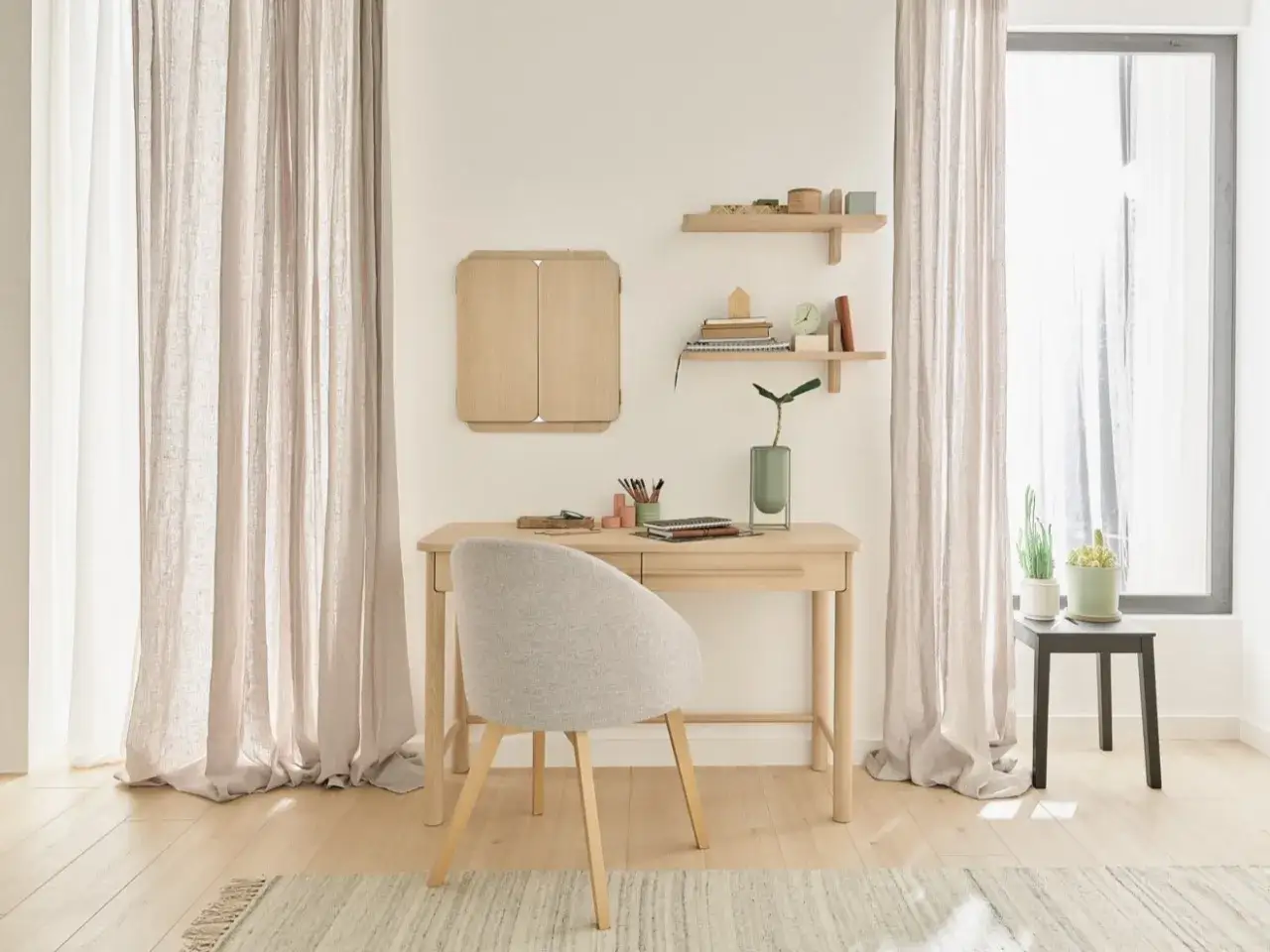 Przytulny pokój z biurkiem i wygodnym fotelem do toaletki. Jasne zasłony, półki z dekoracjami i rośliny tworzą spokojną atmosferę.