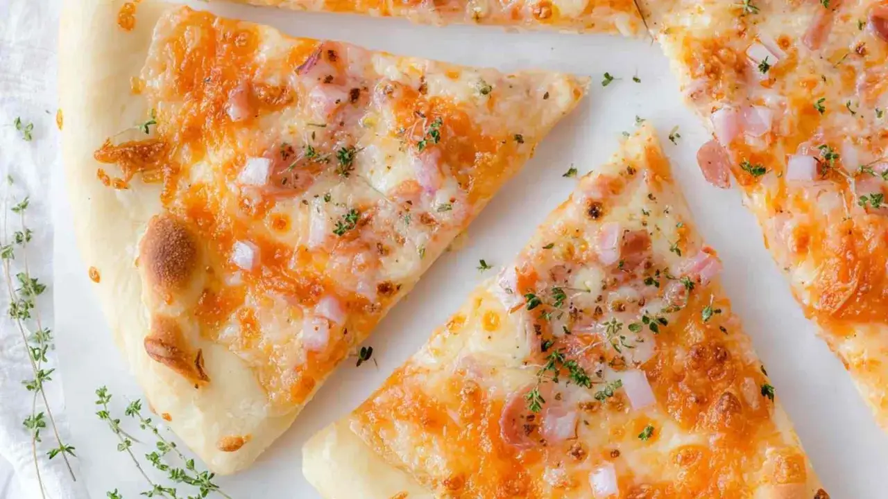 Kawałki pysznej pizzy bez drożdży z ciągnącym się serem, szynką i cebulką, posypane świeżym tymiankiem.