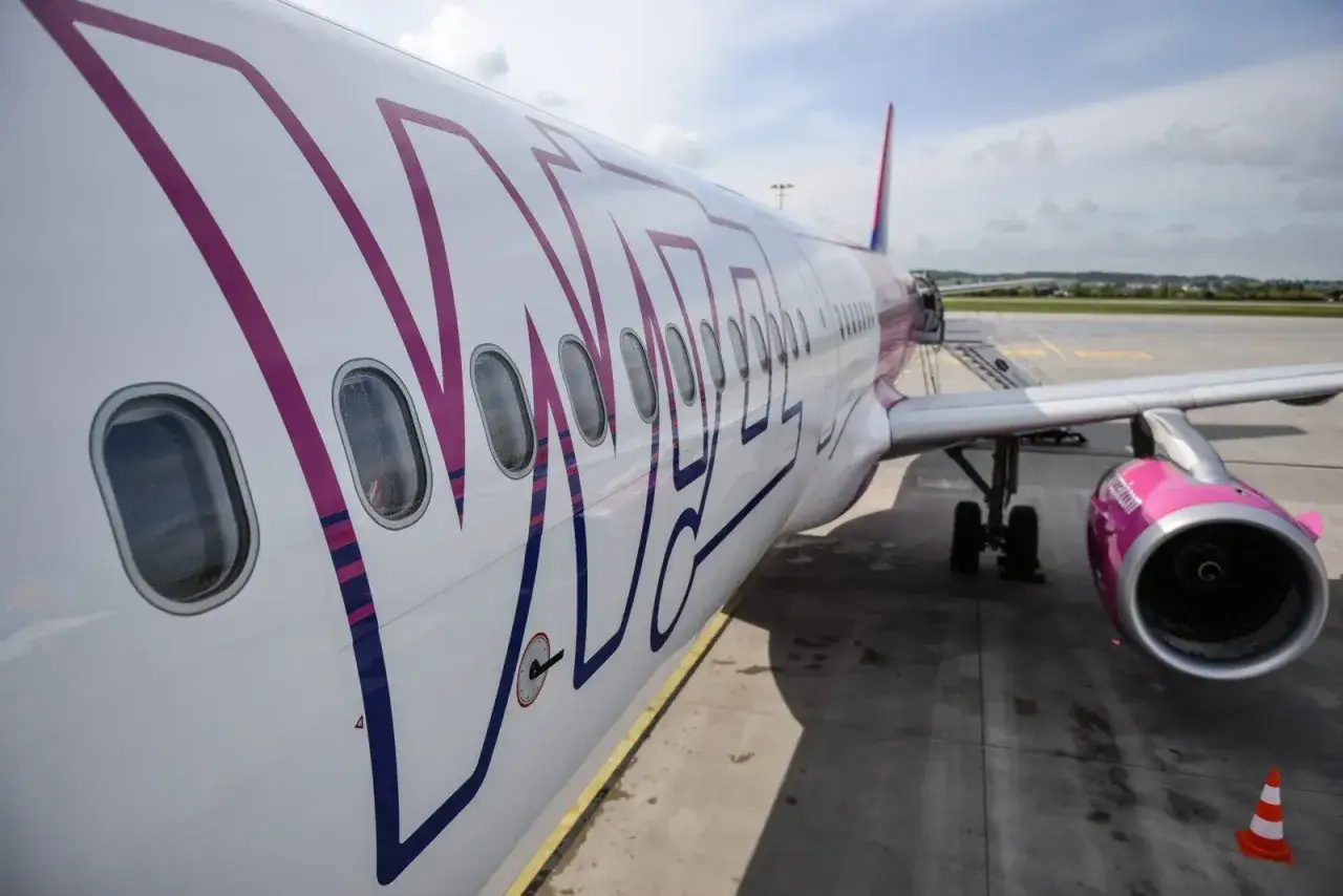 Samolot Wizzair, znanej firmy lotniczej, na płycie lotniska. Różowe logo i silnik.