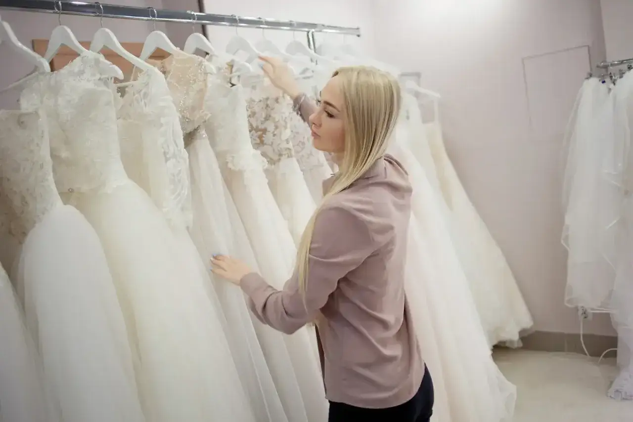Blondynka wybiera suknię ślubną w salonie sukien ślubnych.