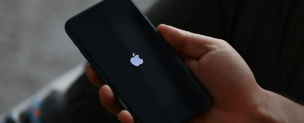Dłoń trzyma iPhone 13 z logo Apple. Czas na reset? Dowiedz się, jak zresetować iPhone 13.