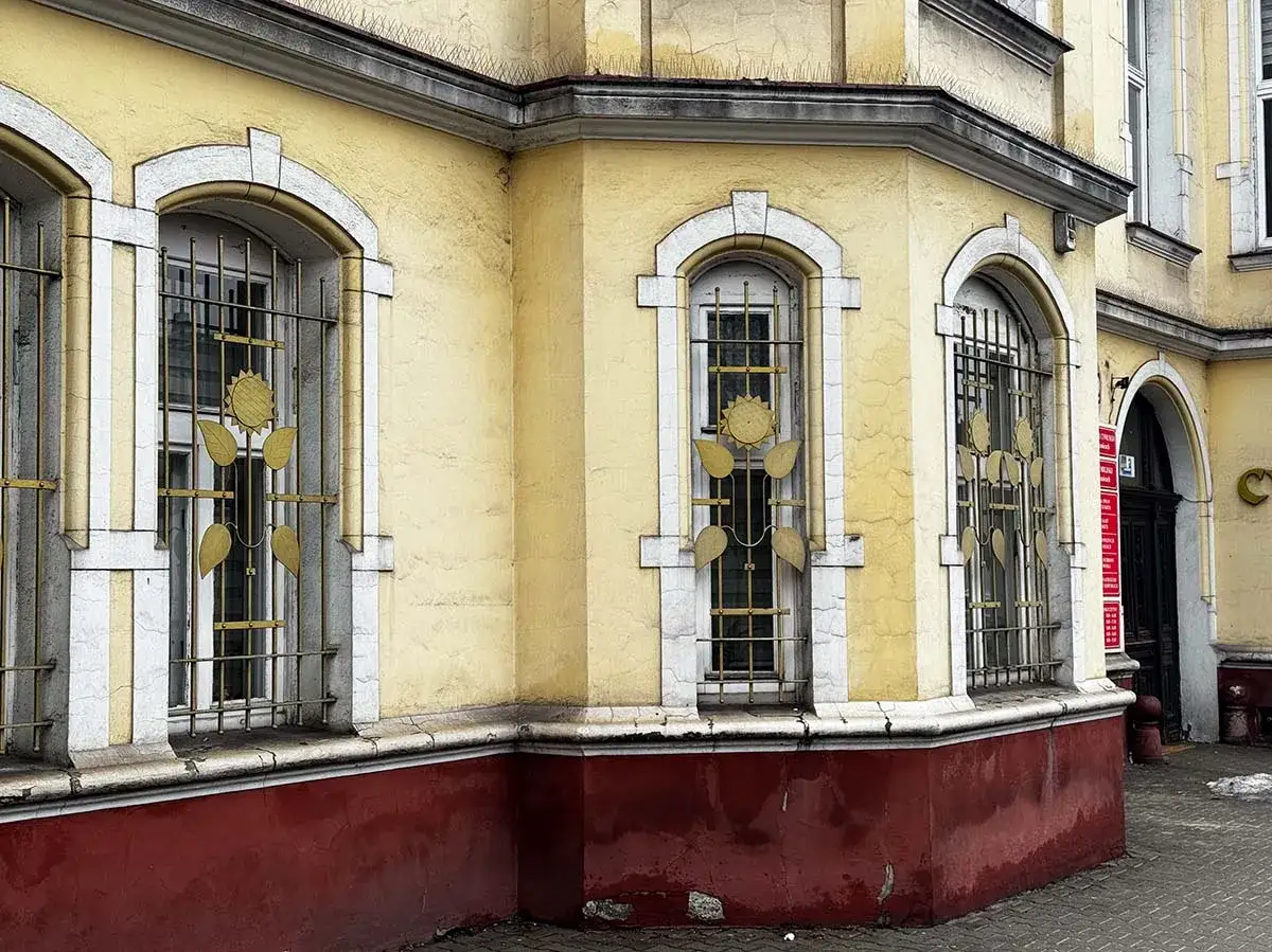 Żółty budynek z ozdobnymi kratami okiennymi. Ile lat musi mieć budynek żeby był zabytkiem? Ten z pewnością ma już swoje lata.