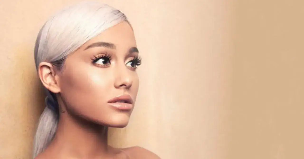 Portret Ariany Grande z blond włosami spiętymi w kucyk, patrzącej w bok.