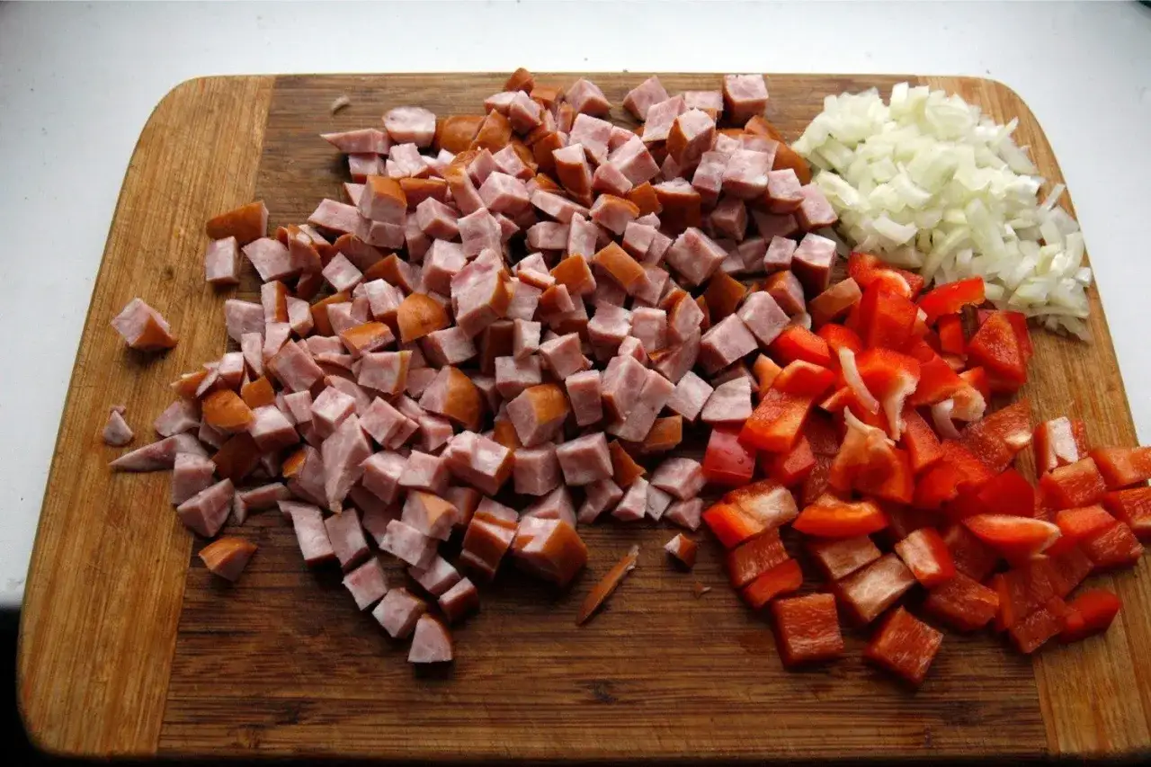 Pokrojona kiełbasa, papryka i cebula na desce do krojenia, gotowe do przygotowania pysznego leczo z kiełbasą.