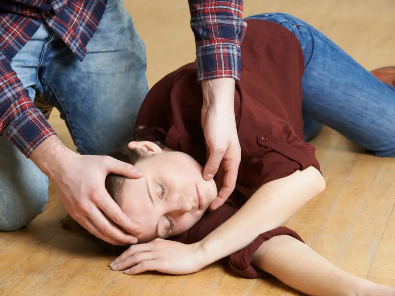 Osoba w pozycji bocznej bezpiecznej, z ręką pod głową, na podłodze.