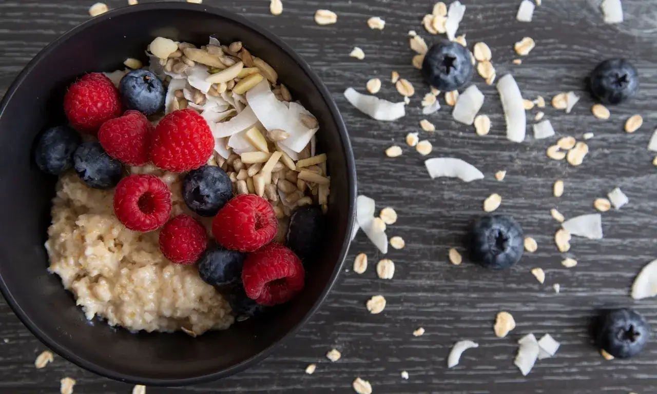Pyszny przepis na zdrową owsiankę z malinami, borówkami i wiórkami kokosowymi. Idealne śniadanie pełne witamin.