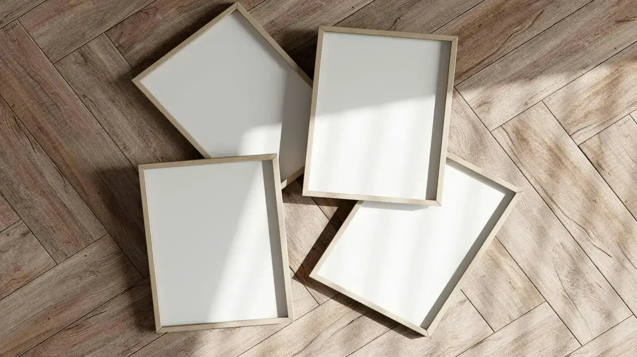Cztery puste, drewniane ramki na obrazy leżą na drewnianej podłodze.