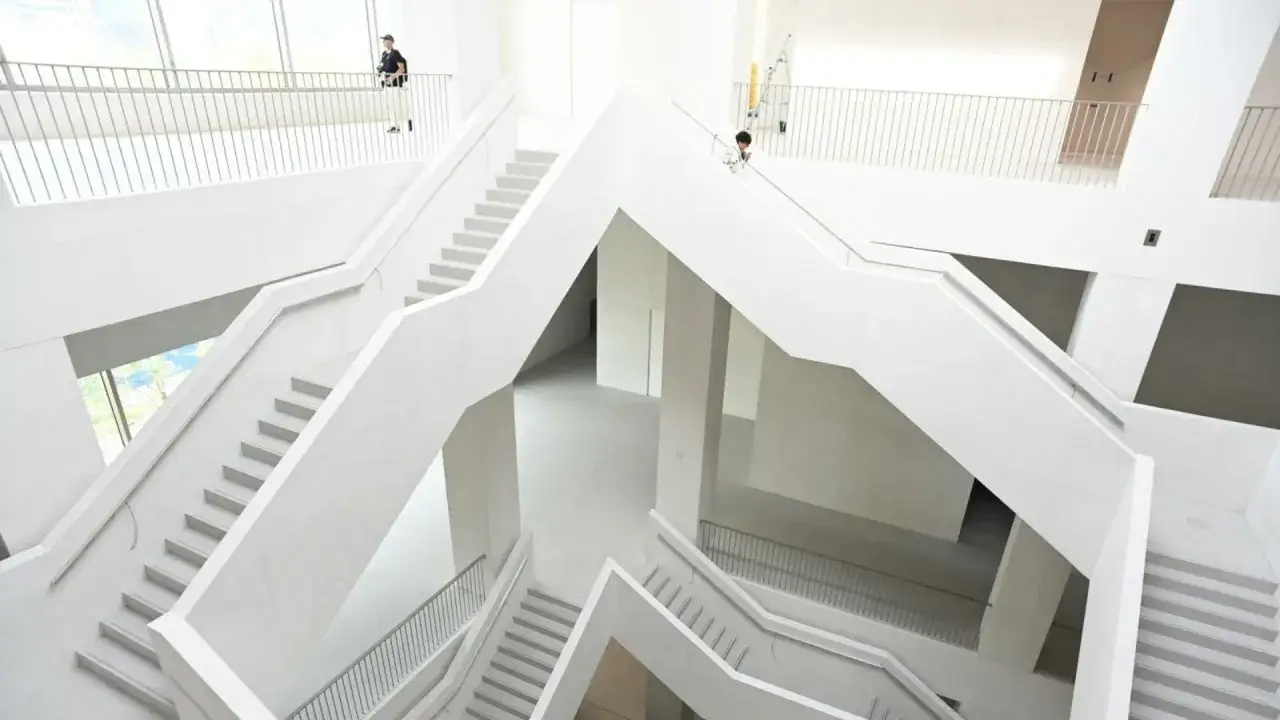 Nowoczesne, białe wnętrze muzeum z wielopoziomowymi schodami i balustradami.