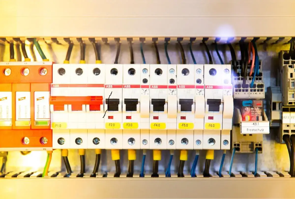 Wnętrze rozdzielni elektrycznej z widocznymi zabezpieczeniami, przewodami i elementami sterującymi.