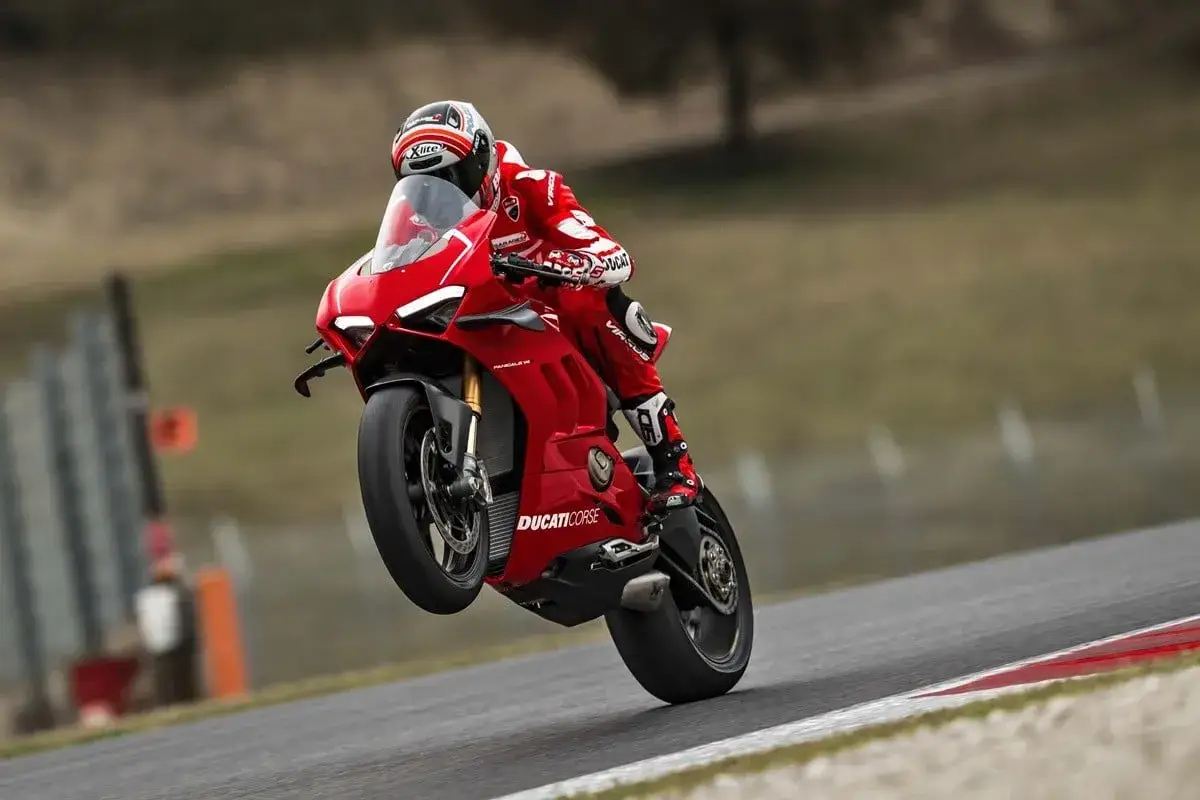 Czerwona Ducati Panigale V4R na torze, z przednim kołem w powietrzu. Kierowca w kombinezonie Ducati Corse.