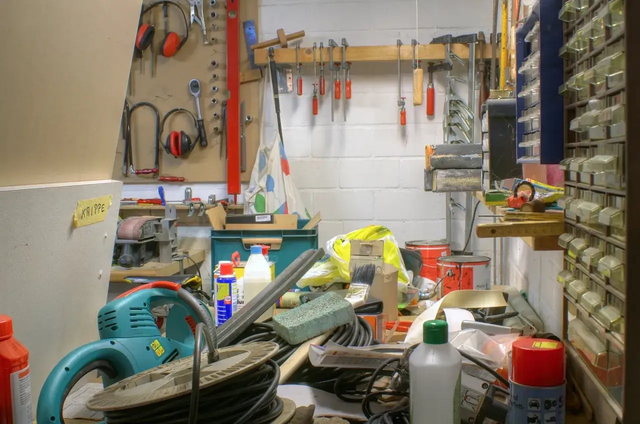 Warsztat w piwnicy w bloku: narzędzia, kable, puszki farby i organizer na drobne części.