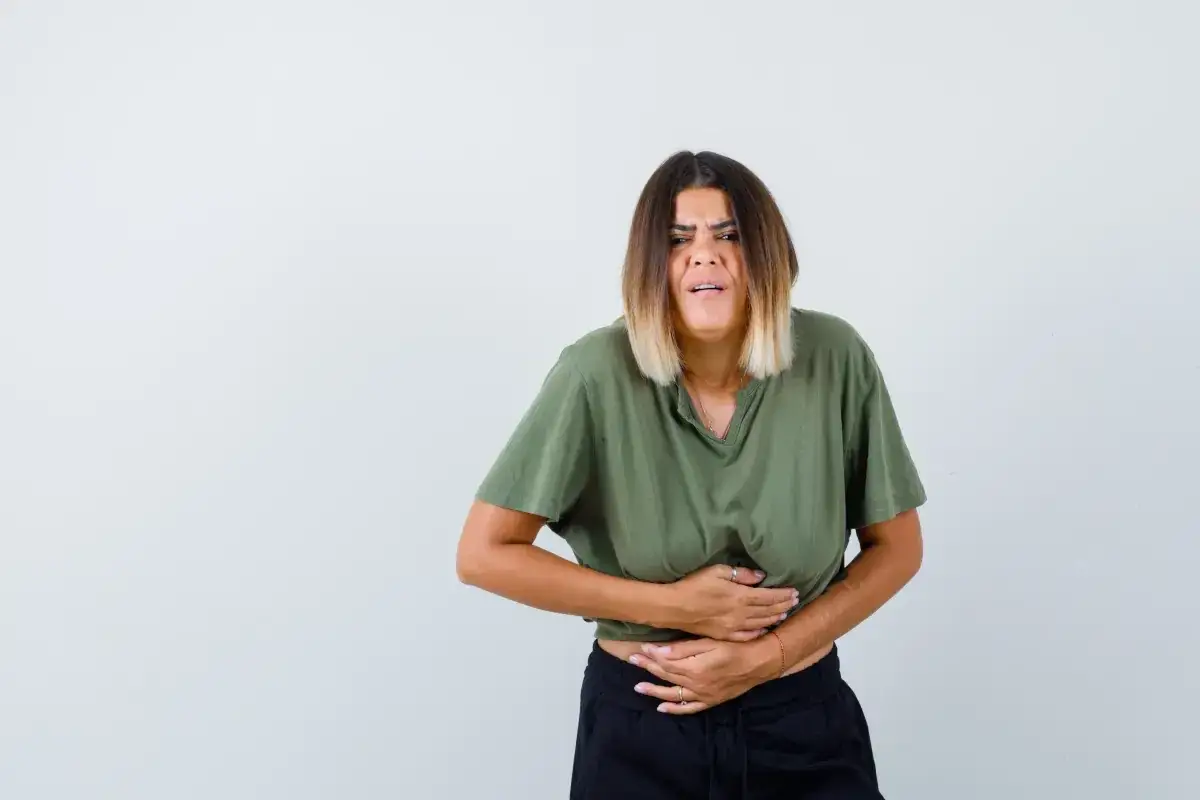 Kobieta z bólem brzucha, trzymająca się za lewą stronę, gdzie mogą znajdować się narządy.