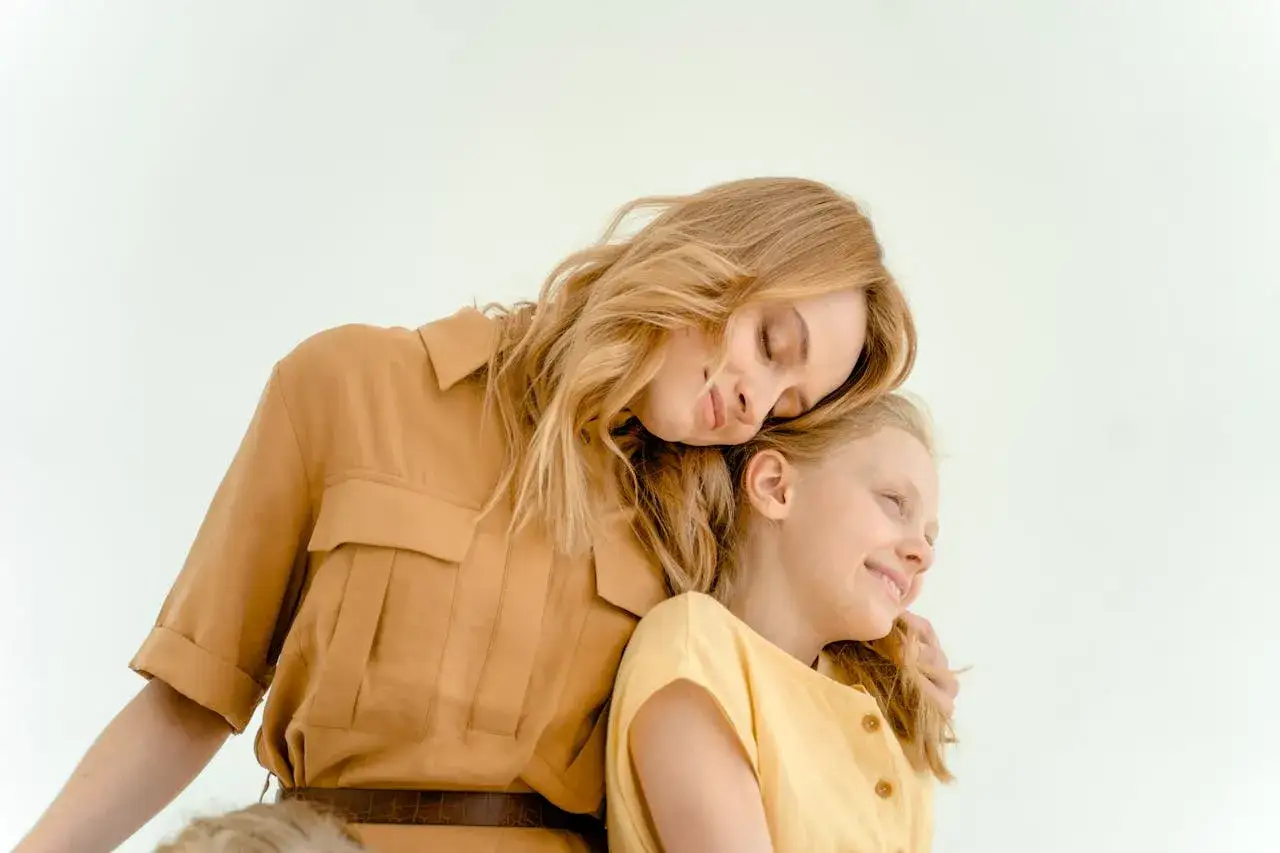 Matka w stroju w kolorze camel przytula córkę. Ten ciepły odcień pasuje do wielu typów urody, podkreślając naturalne piękno.