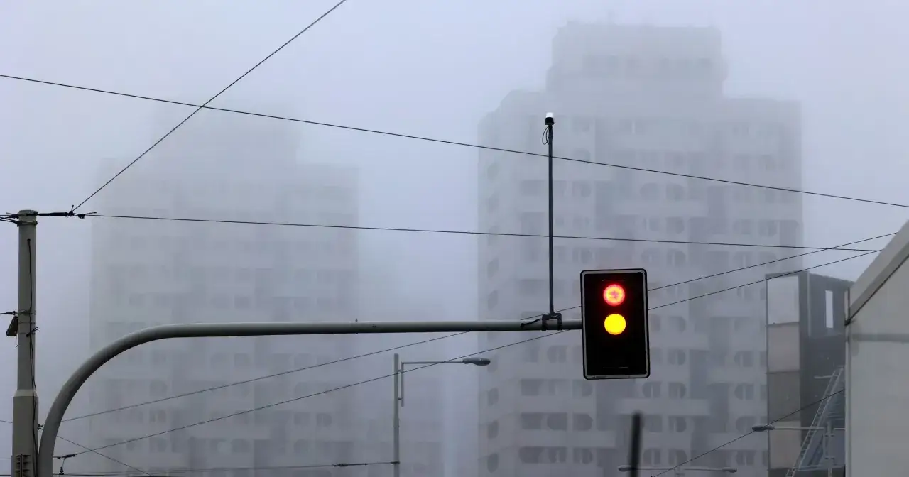 Mgła tak gęsta, że czuć ją w powietrzu. Sygnalizacja świetlna pokazuje czerwone i żółte światło, budynki znikają we mgle.