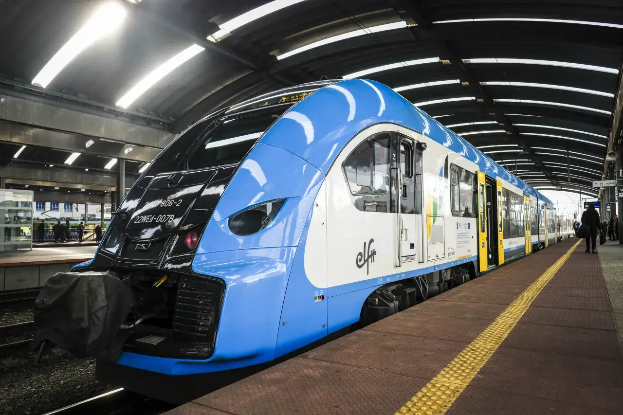 Niebiesko-biały pociąg PKP na peronie. Zastanawiasz się, jak zwrócić bilet PKP kupiony przez internet bez rejestracji? Sprawdź procedury online.