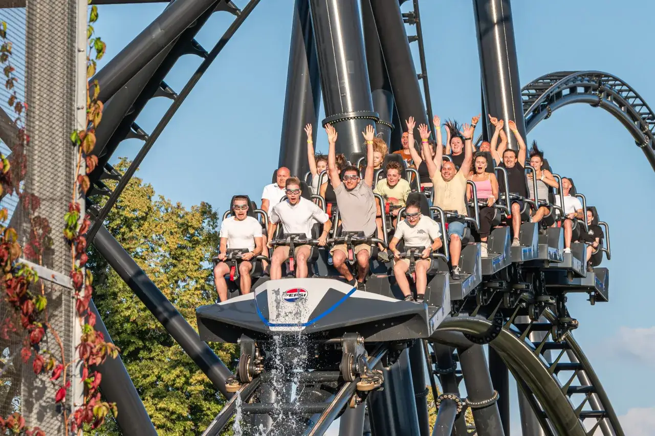 Ludzie na kolejce górskiej Hyperion w Energylandii, z rękami w górze, krzyczący z ekscytacji.