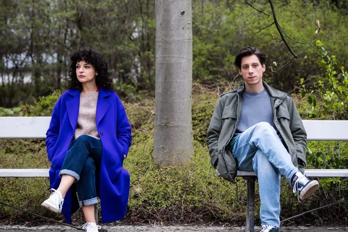 Para z serialu "Kiedy ślub" siedzi na ławce w parku, oddzielona drzewem.