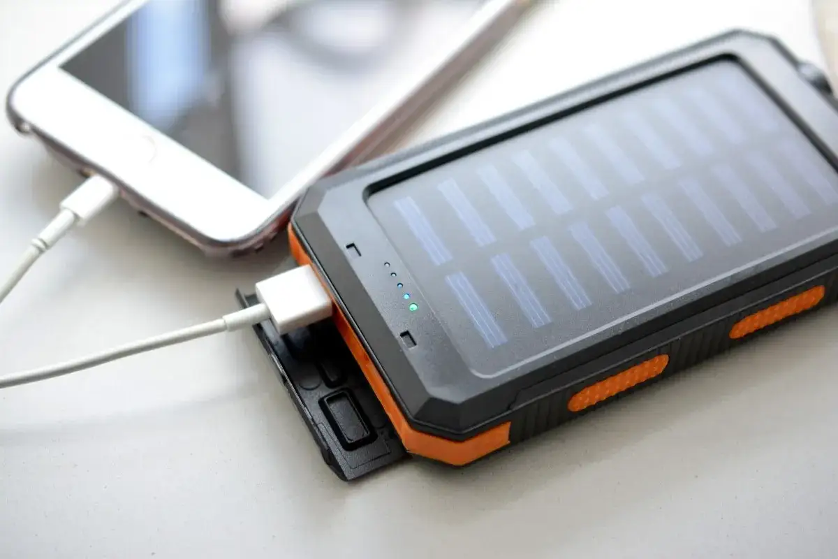 Ładowanie słuchawek bezprzewodowych ładowarką do telefonu jest możliwe, jeśli mają ten sam typ złącza. Na zdjęciu widać powerbank z panelem słonecznym ładujący telefon.