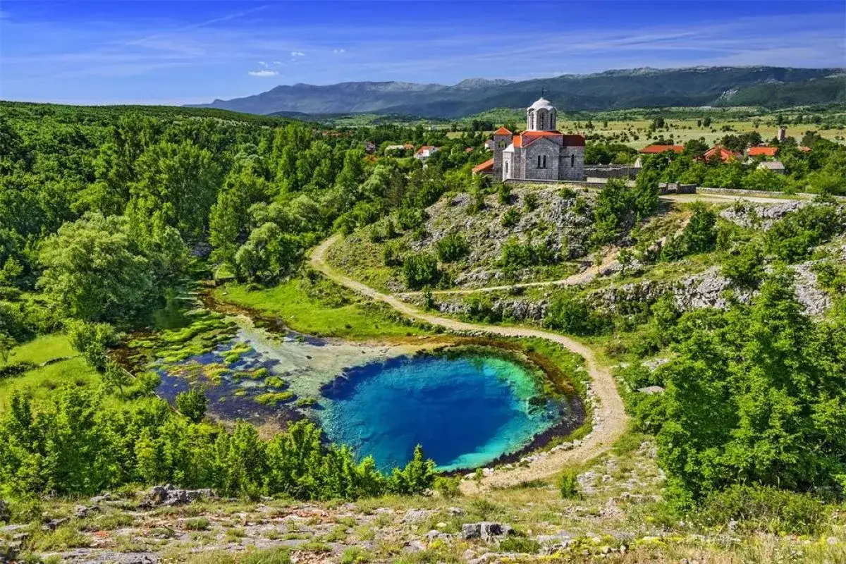 Niebieskie "oko ziemi" w Chorwacji, źródło rzeki z kościołem na wzgórzu w tle.