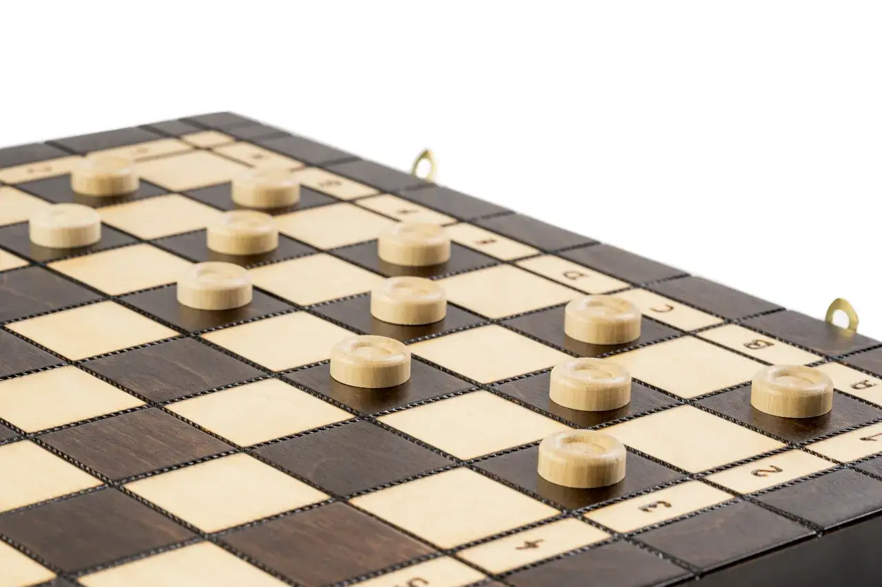Drewniana plansza do warcabów z kilkoma białymi pionkami.