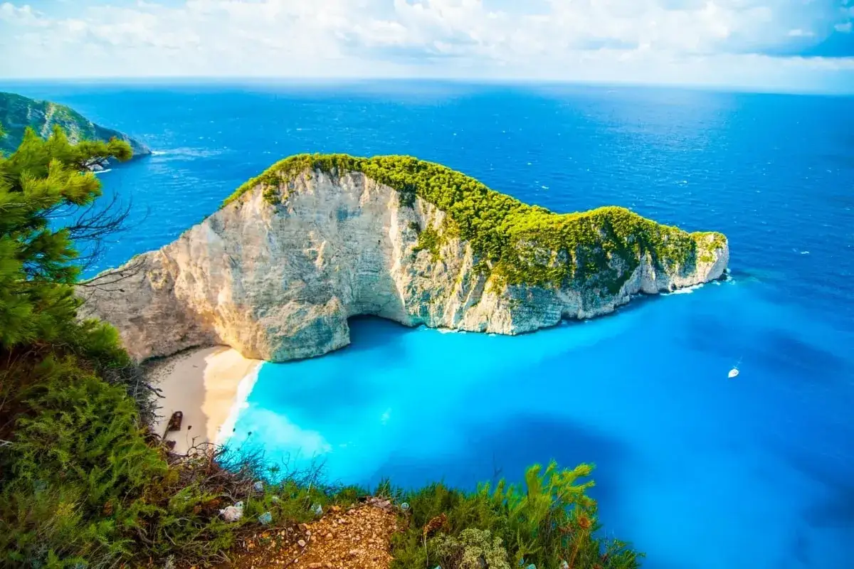 Widok na zatokę Navagio, gdzie do Grecji? Białe klify, turkusowa woda i zielona roślinność tworzą rajski krajobraz.