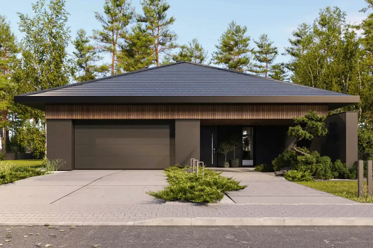 Nowoczesny dom z garażem, przed którym rozciąga się podjazd z płyt betonowych. Wokół bujna zieleń i wysokie drzewa.