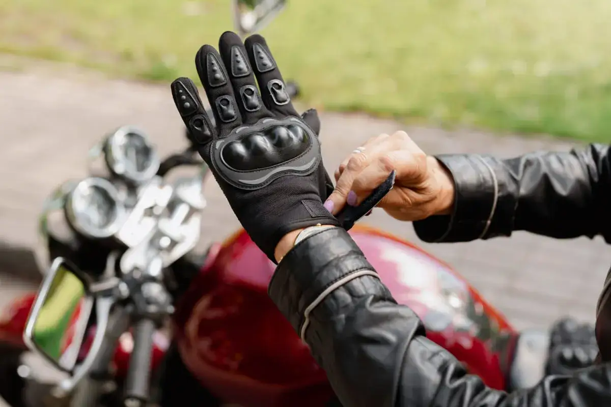 Motocyklista zapina rękawicę z ochraniaczami. Różne rodzaje ochraniaczy zapewniają bezpieczeństwo.
