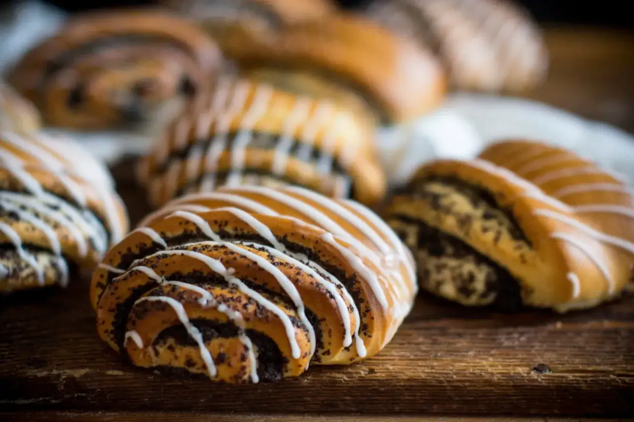 Drożdżówki z makiem polane lukrem na drewnianym tle.