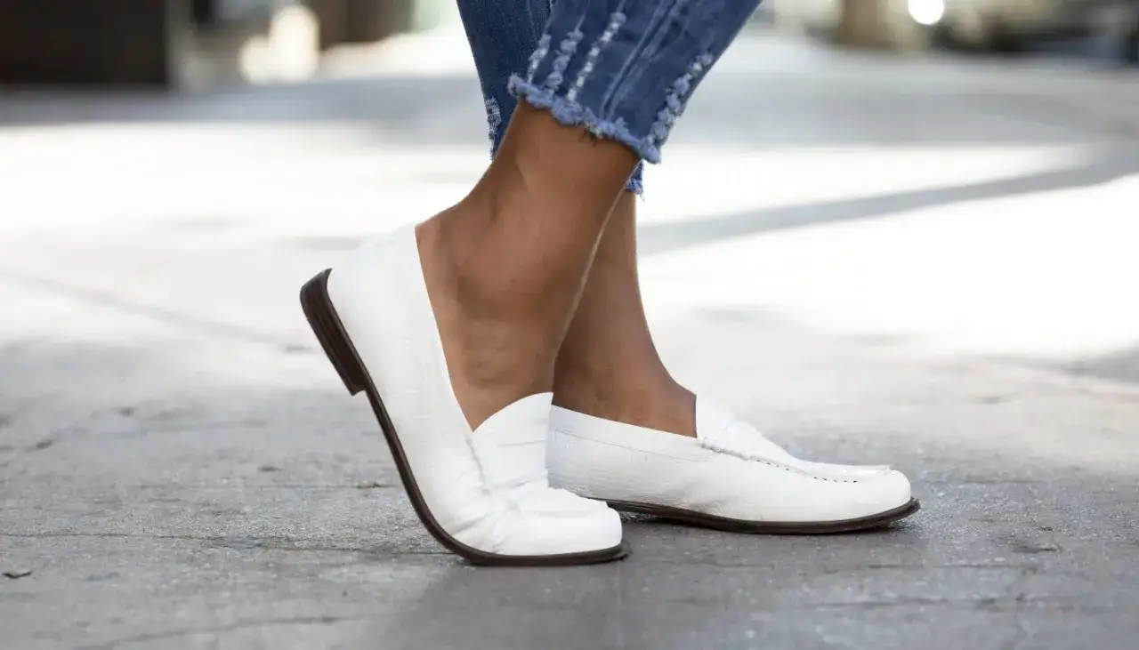 Białe mokasyny damskie w stylizacjach z jeansami z postrzępionymi nogawkami. Klasyka i wygoda na co dzień.