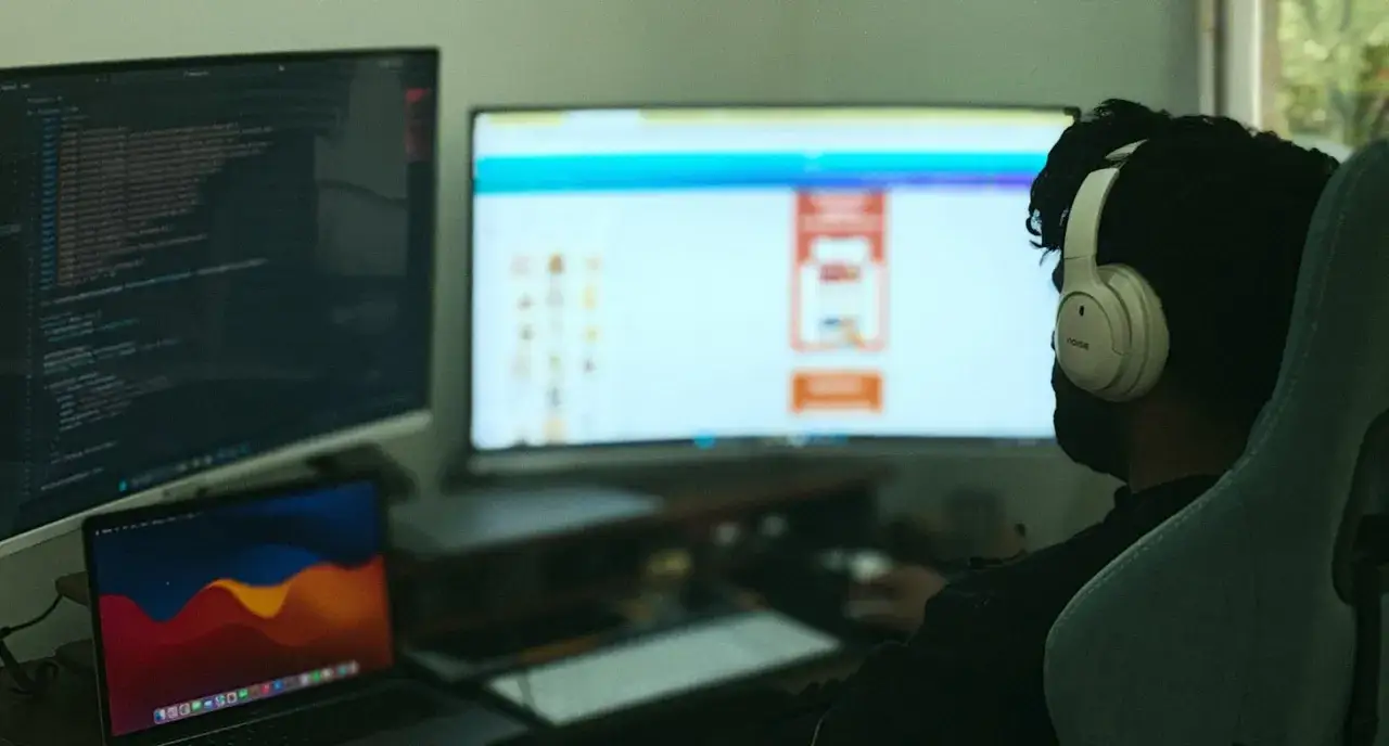 Programista w słuchawkach pracuje nad kodem w C++, widoczny jest ekran z kodem i interfejsem.