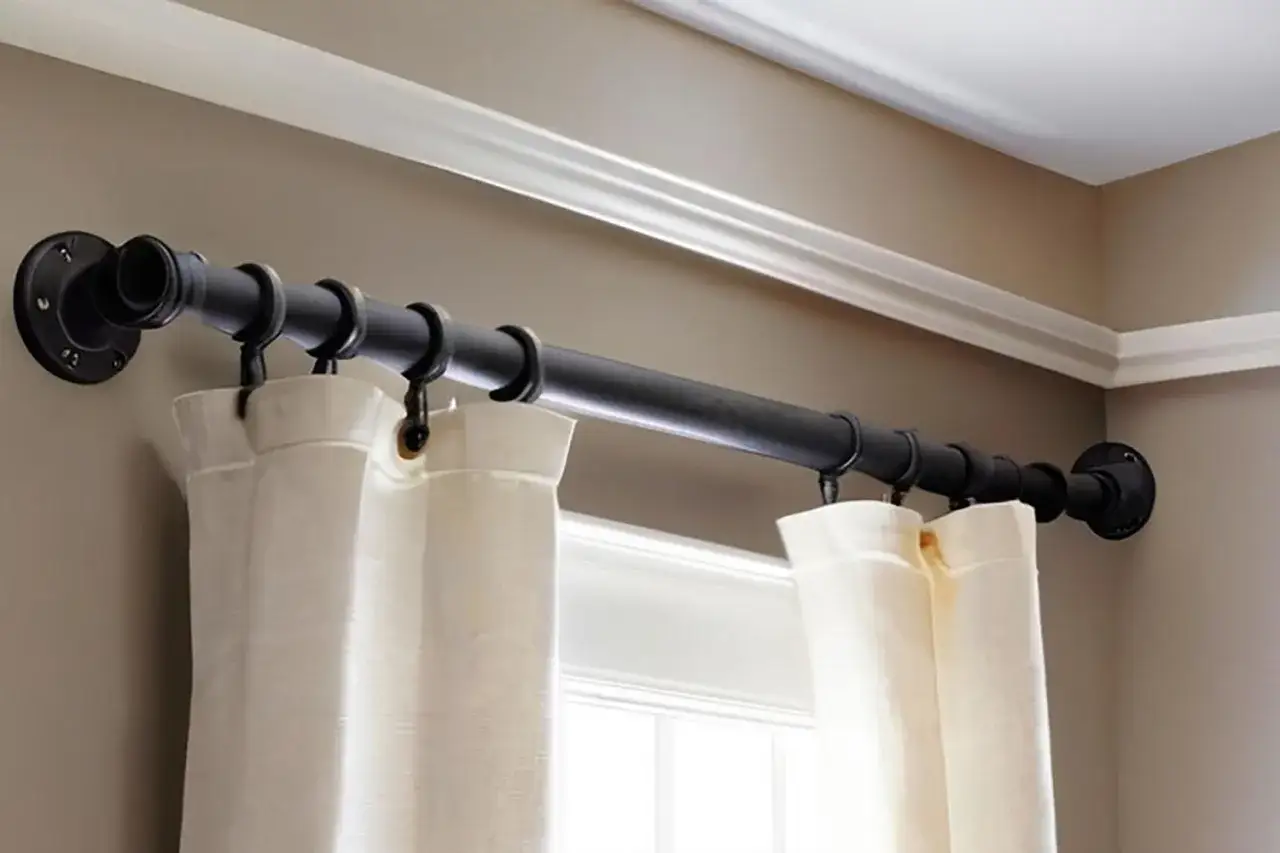 Czarny, industrialny karnisz do sufitu lub ściany, zamontowany nad oknem, z białymi zasłonami.