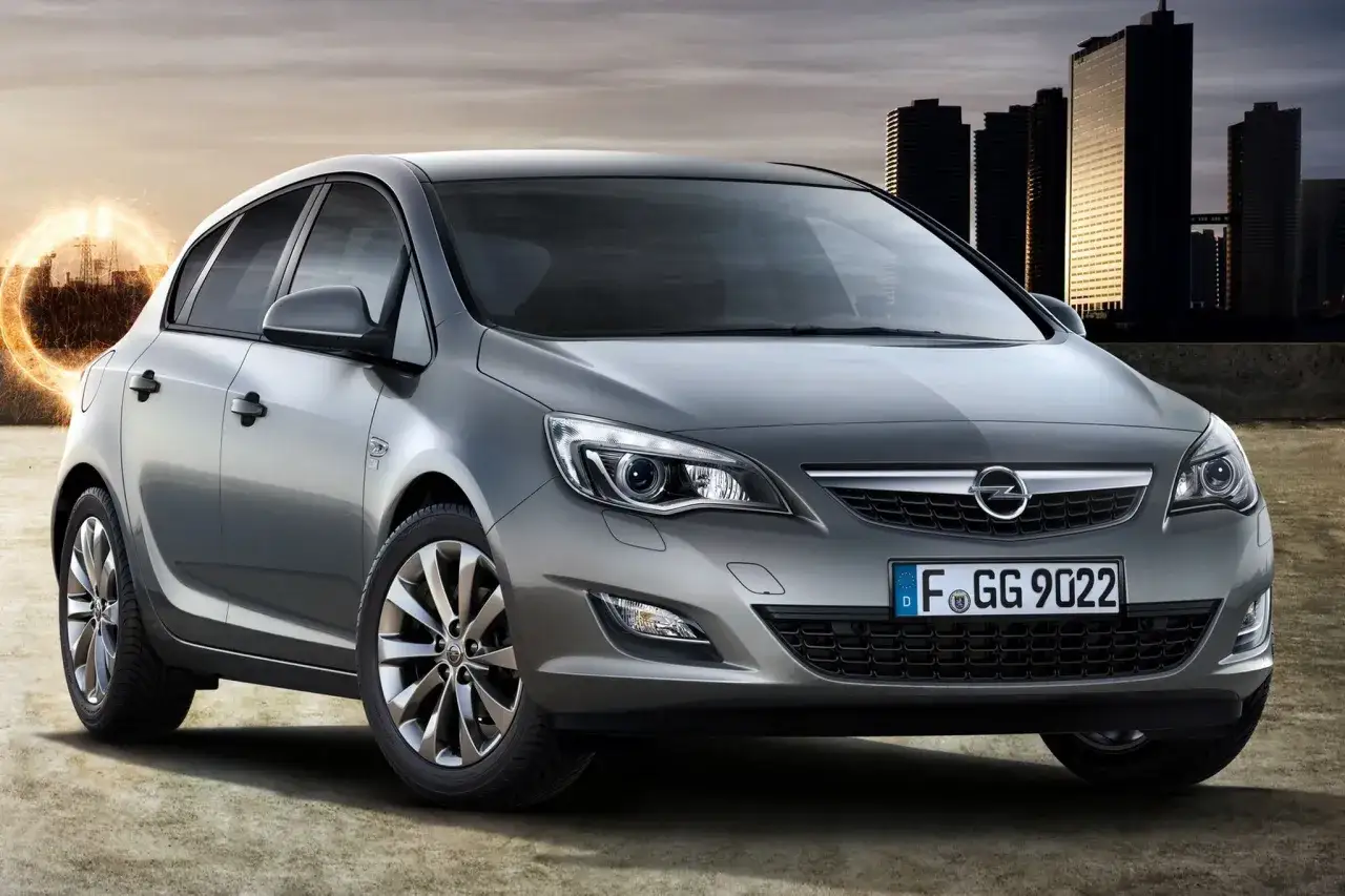 Szary Opel Astra J 1.4 Turbo z felgami i tablicą rejestracyjną F GG 9022 na tle miasta.