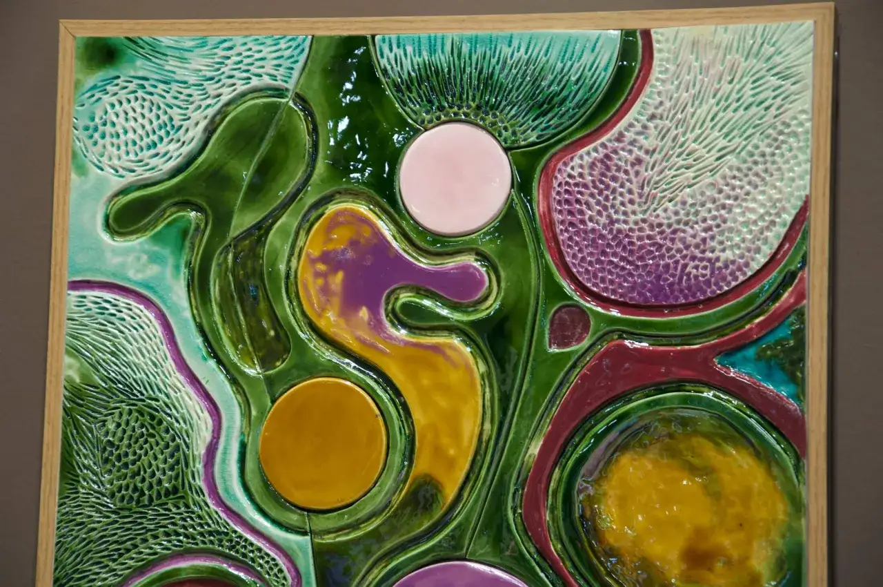 Kolorowy, abstrakcyjny relief wklęsły z ceramicznymi elementami o organicznych kształtach i różnorodnych fakturach.