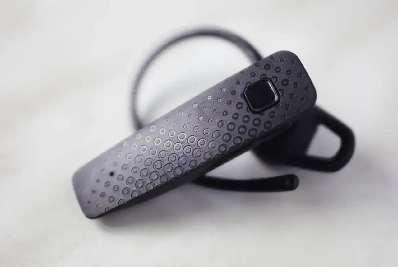 Czarna słuchawka Bluetooth z teksturą kółek. Dowiedz się, jak sparować słuchawki z telefonem.
