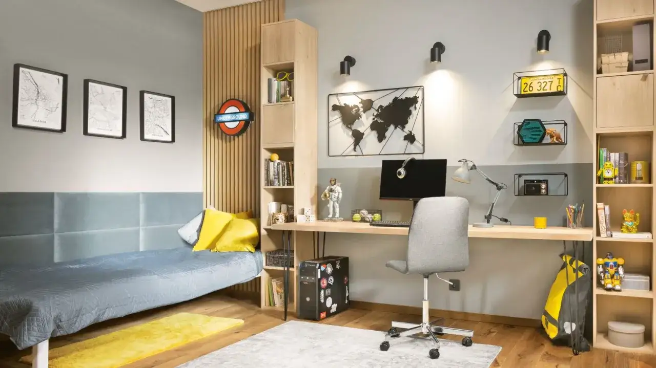 Pokój młodzieżowy z biurkiem, łóżkiem i regałami. Dwa kinkietowe lampy nad biurkiem sugerują, jakie oświetlenie do pokoju wybrać, by stworzyć przytulną atmosferę.