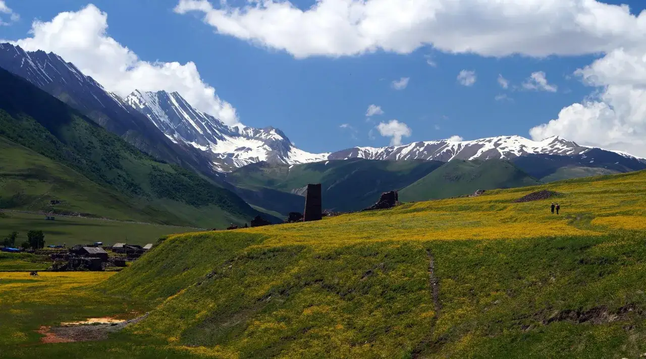 Górzysty krajobraz Gruzji z kwitnącymi polami i wieżami. Ceny w Gruzji są przystępne, a widoki zapierają dech.