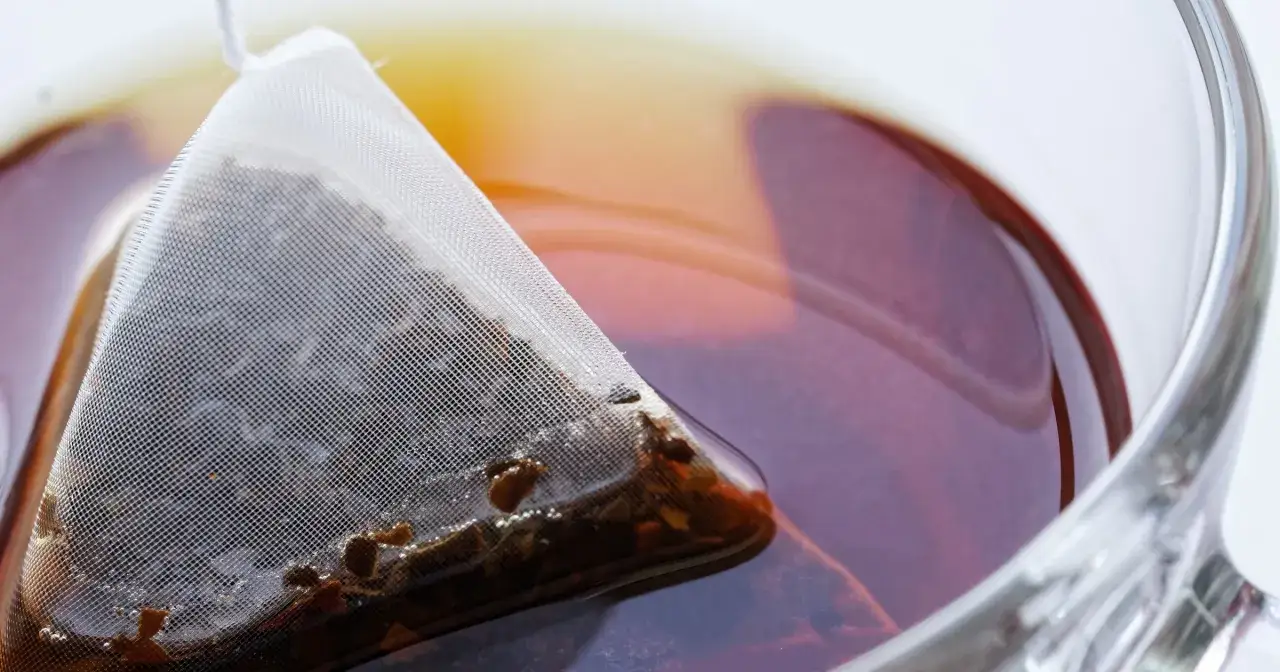 Zaparzona herbata w piramidce, idealna jako **jaka herbata na zaparcia**. Napar ma bursztynowy kolor, a w szklance widać odbicia światła.