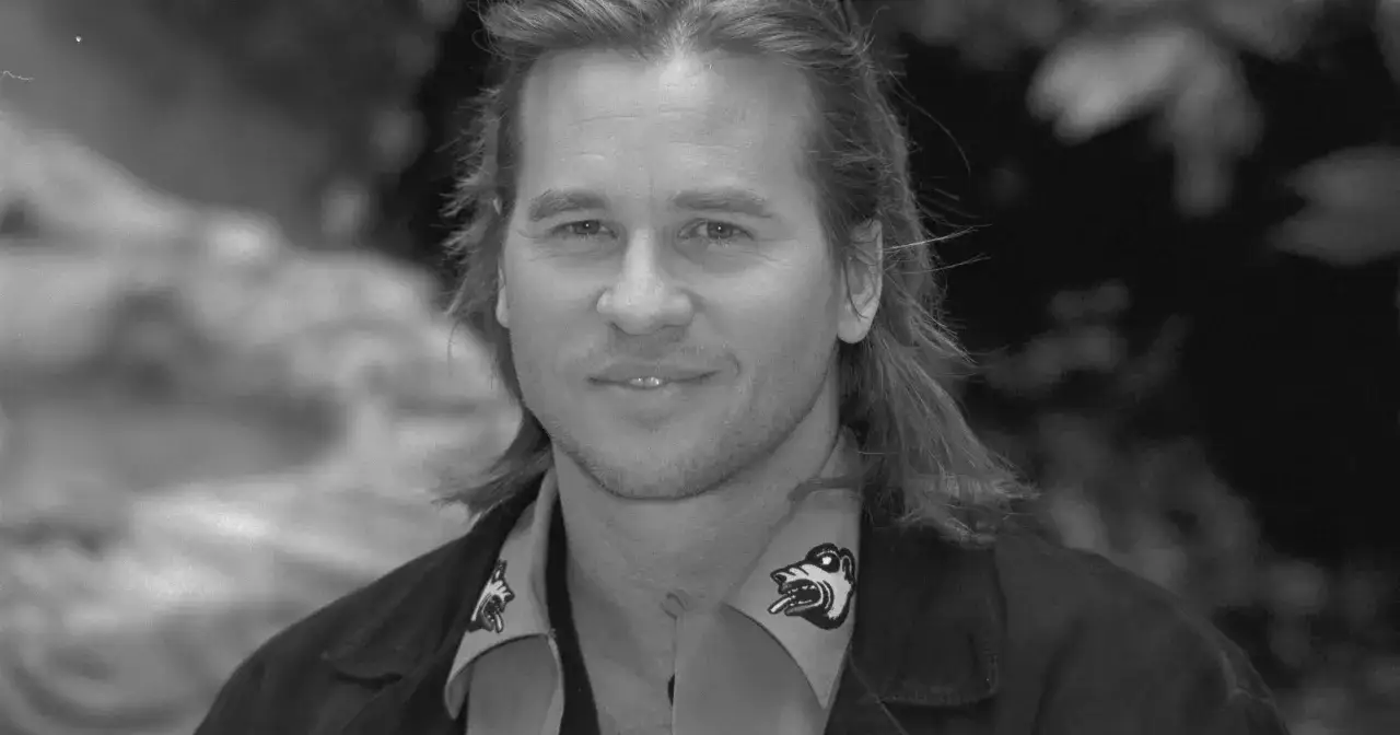 Val Kilmer, znany z wielu filmów, uśmiecha się do obiektywu. Jego charakterystyczna koszula z nadrukiem dodaje mu uroku.