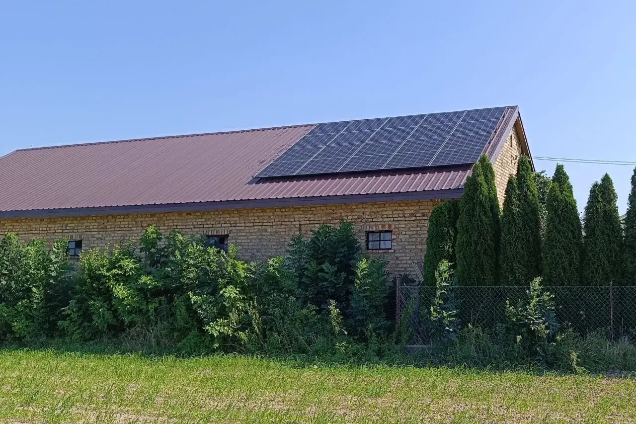Panele fotowoltaiczne na dachu ceglanego budynku, symbolizujące sprzedaż energii z fotowoltaiki.