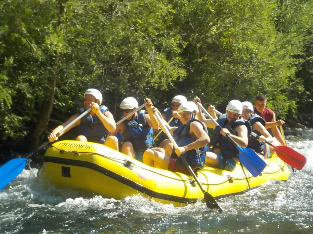 Grupa ludzi na raftingu na rzece Cetina w Chorwacji, wiosłując przez bystrza.