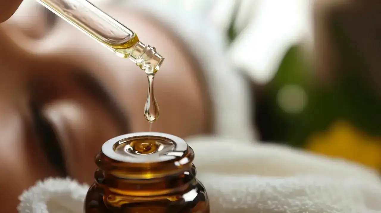 Kropla olejku z drzewa herbacianego do twarzy spada do buteleczki. Delikatna pielęgnacja dla Twojej skóry.